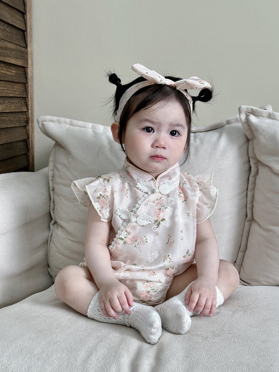 Baby wearing the Cherry Blossom pink floral cheongsam-style romper with bow headband