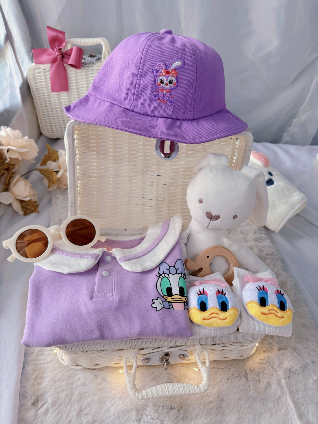 Little Daisy premium baby gift set in a rattan basket with lilac duck-collar romper with bucket hat
