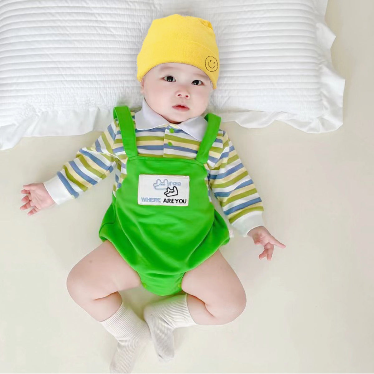 Baby wearing the Little Green Sprout green striped romper with yellow hat