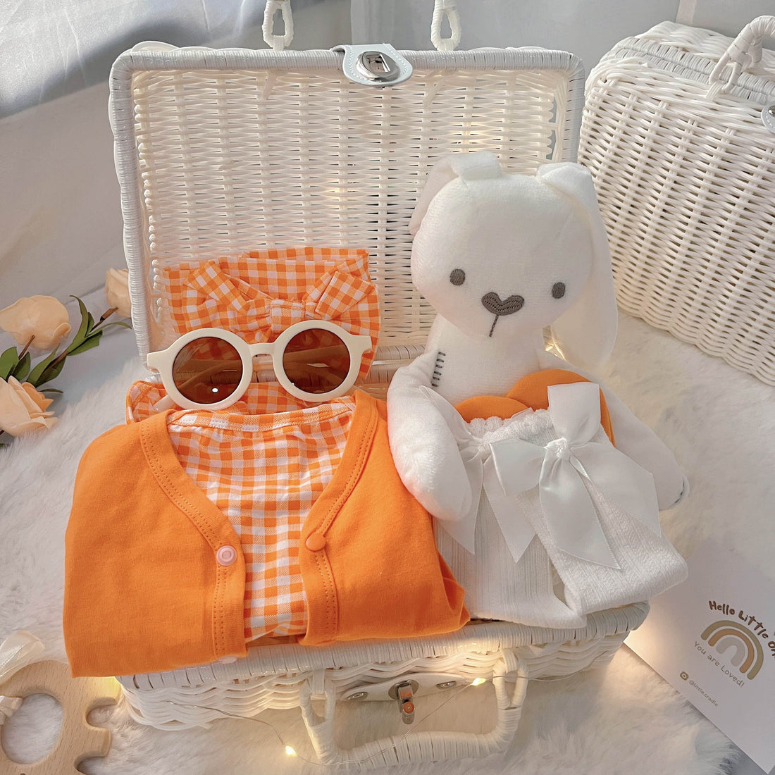 Orange Buttercup premium baby gift set in a rattan basket with orange romper and cardigan
