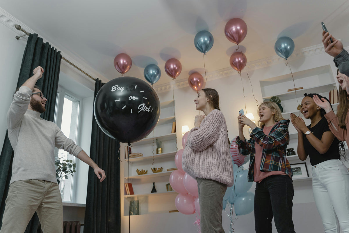 Parents celebrating a baby gender reveal party with balloons