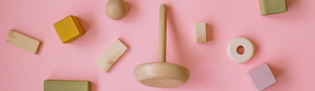 Wooden baby toys on a pink background