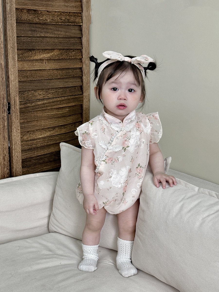 Baby wearing the Cherry Blossom pink floral cheongsam-style romper with bow headband