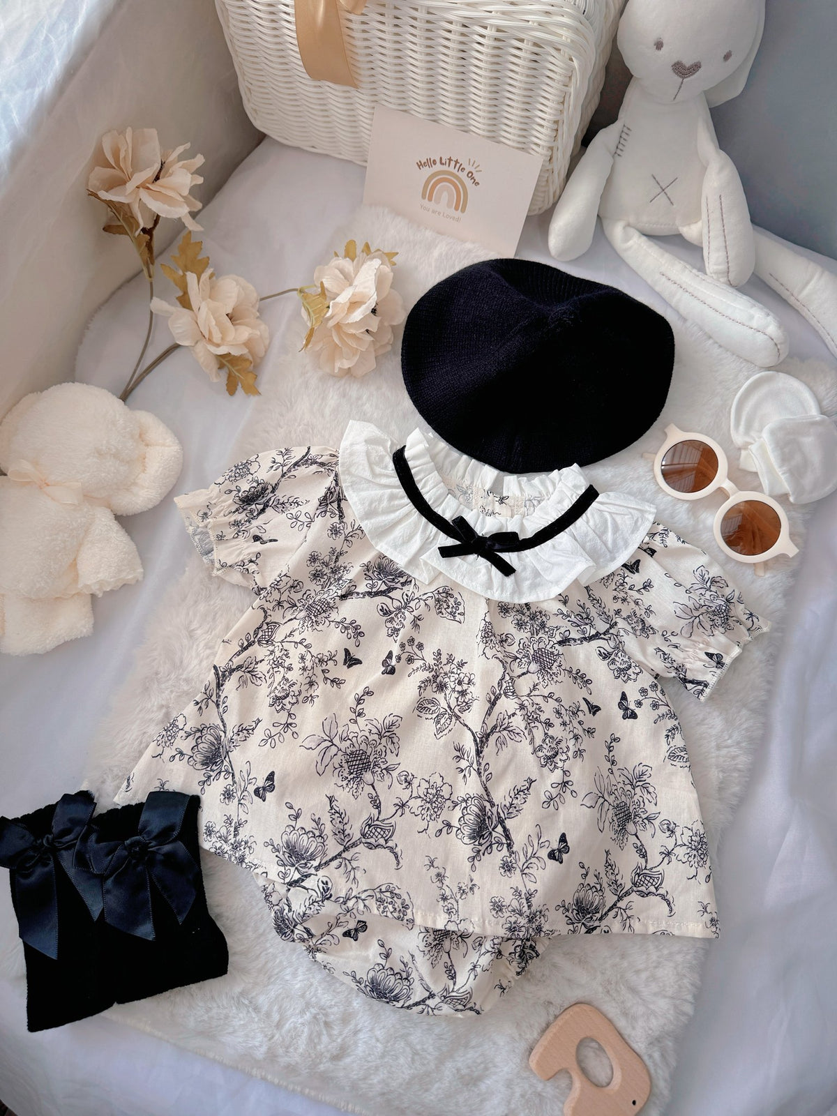French Blossom baby outfit flat lay – floral romper with ruffled collar and black beret