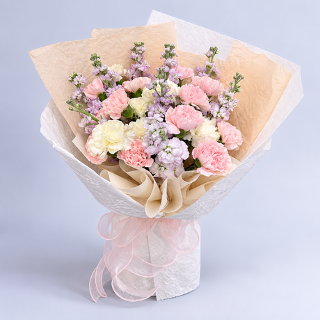 Pastel Symphony Bouquet — pink and cream carnations with lilac flowers, complete bouquet on a clean neutral background