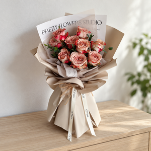 Adore Cappuccino Rose Bouquet with cappuccino roses and cream ribbon in a softly lit neutral interior.