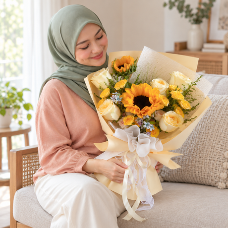 Dawn Sunflower & Yellow Rose Bouquet held by the same recipient in a seated candid pose.