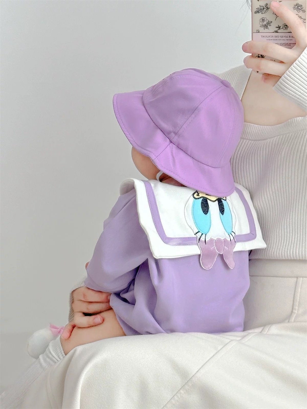 Baby wearing the Little Daisy lilac duck-collar romper with bucket hat