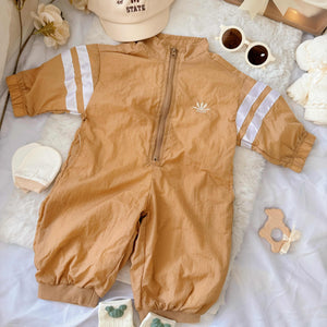 Flat lay view of Little Explorer baby hamper – sporty zip-up romper, sunglasses, matching hat, baby socks, towel bear and mittens