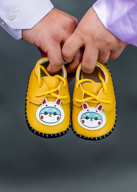 Parents holding a pair of yellow baby shoes
