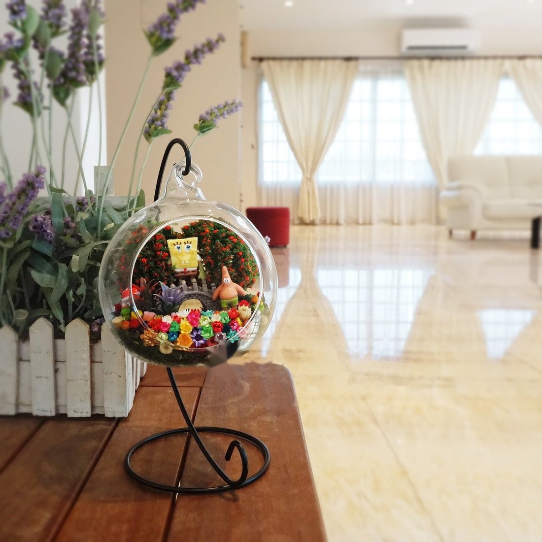 Terrarium kaca bulat dengan patung haiwan laut di antara bunga awet
