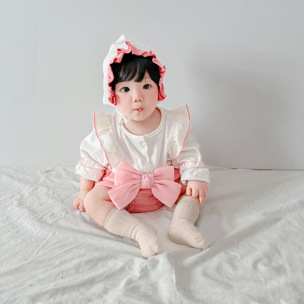 Baby wearing the Strawberry Mochi pink romper with ribbon accent