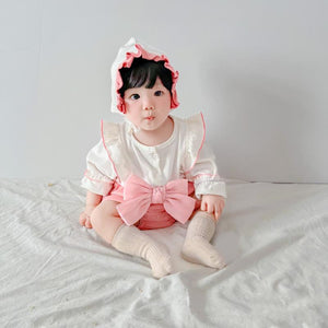 Baby wearing the Strawberry Mochi pink romper with ribbon accent